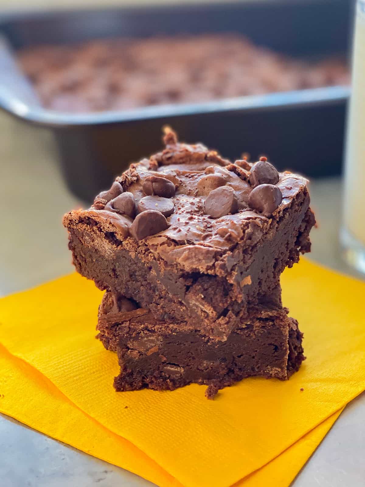 Two brownies stacked on top of each other on yellow napkins. 