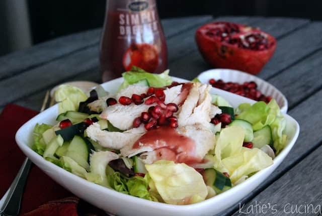White square bowl on a wood table filled with salad and turkey.