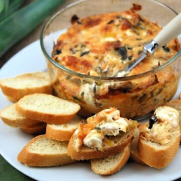 Glass bowl with dip with slices of baguette and dip on baguettes on a plate.