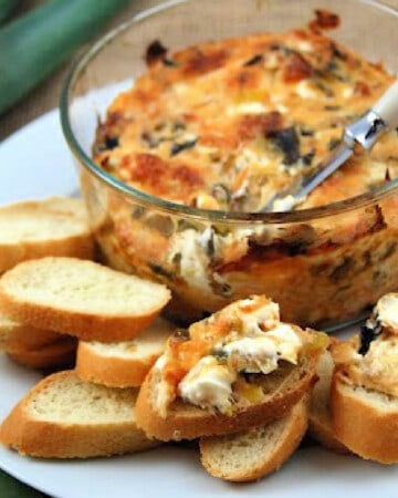 Glass bowl with dip with slices of baguette and dip on baguettes on a plate.