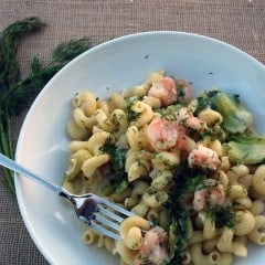 Top view of a white bowl filled with cork screw pasta, greens, and shrimp with text on image for pinterest.