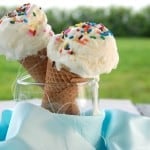 Two ice cream cones filled with white ice cream with sprinkles on top.