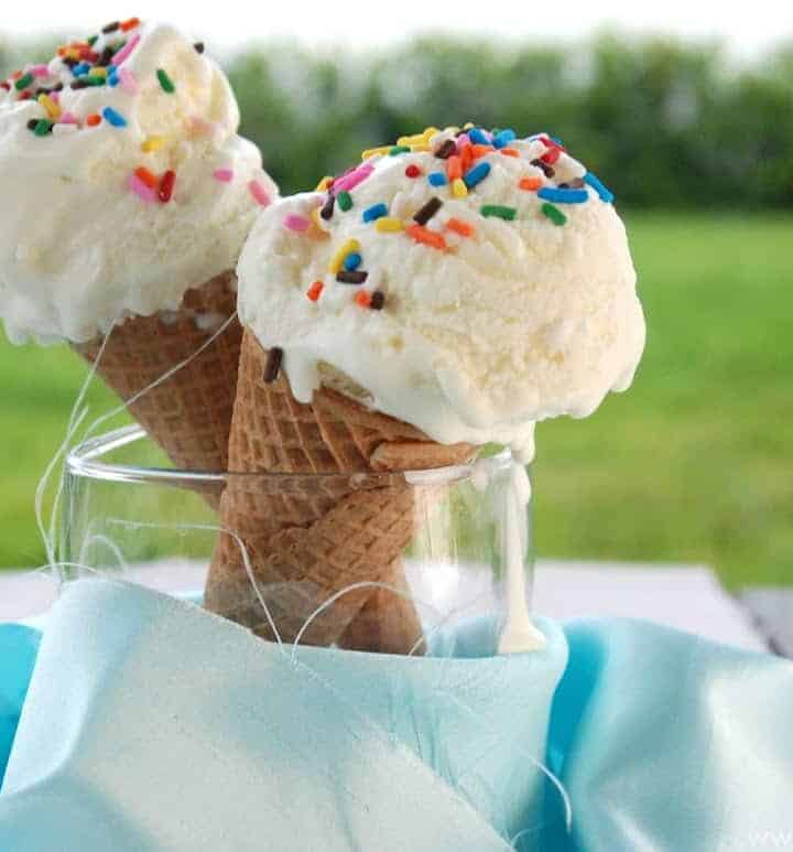 Two ice cream cones filled with white ice cream with sprinkles on top.