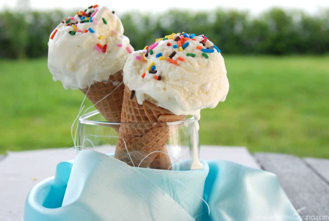 Two ice cream cones filled with white ice cream with sprinkles on top.