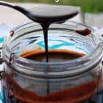 Spoon with chocolate sauce drizzling over jar.