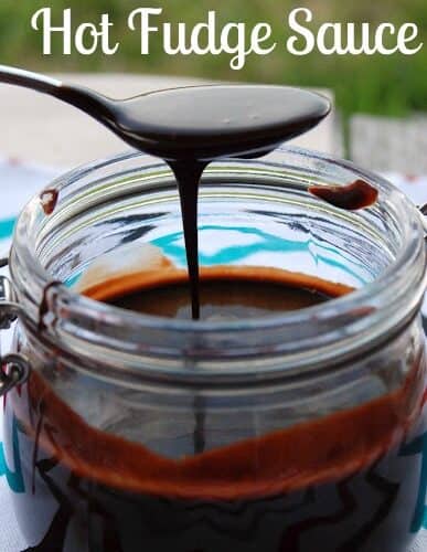 Spoon with chocolate sauce drizzling over jar.