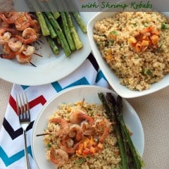 Top view of two plates with shrimp skewers sitting on top of israeli couscous.