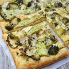 Top view of pastry topped with browned broccoli and shredded cheese.