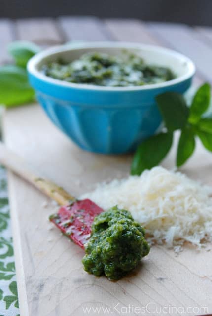 Red silicone spatula with pesto on a cutting board.