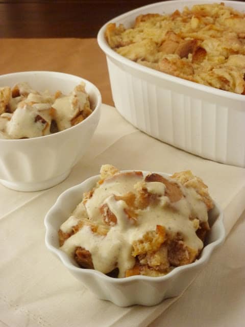 Two bowls filled with bread pudding with sauce .