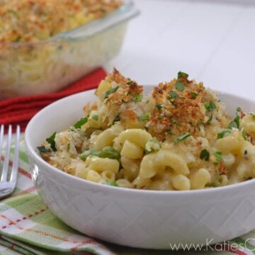 Bowl of cheese macaroni noodles topped with panko breadcrumbs and green herbs.