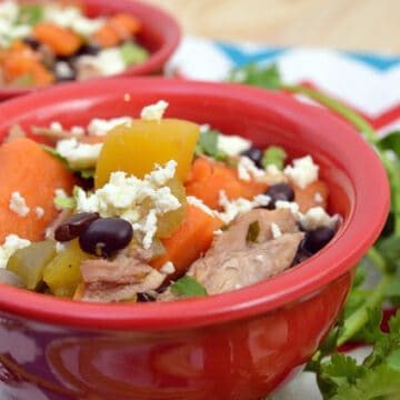 Two red bowls filled with turkey, black beans, vegetables, and broth.