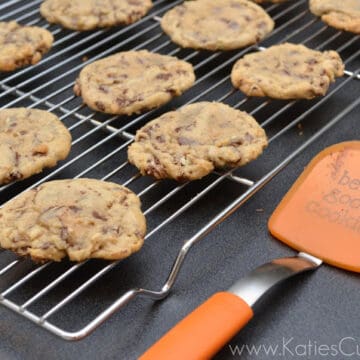 Cookies on a wire cooling rack with a orange spatula next to it.