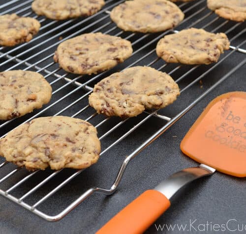 Cookies on a wire cooling rack with a orange spatula next to it.