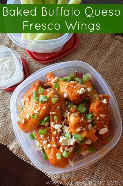 Top view of a plastic container with wings topped with cheese and green onions.