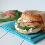 Side view of everthing bagel sandwich with garlic-herb cream cheese, tomato, cucumber, and spinach.