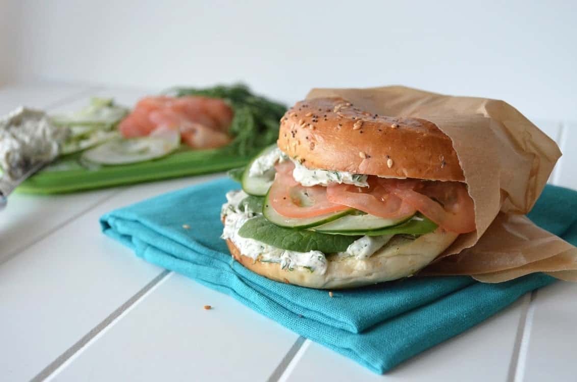 Side view of everthing bagel sandwich with garlic-herb cream cheese, tomato, cucumber, and spinach.