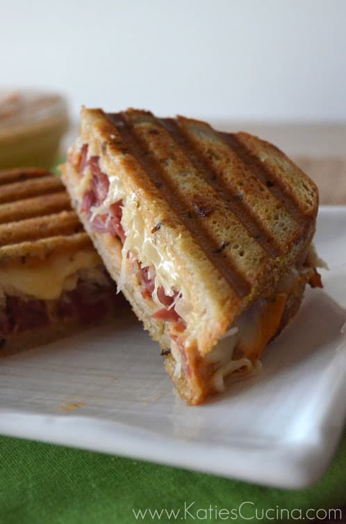 Plated sliced reuben sandwhich with sauce, sauerkraut, meat, and cheese displayed.