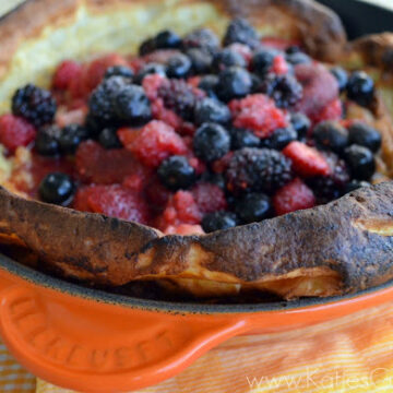 Golden Brown Pastry with edges rising over top of skillet with mixed berries on top of pastry's center.
