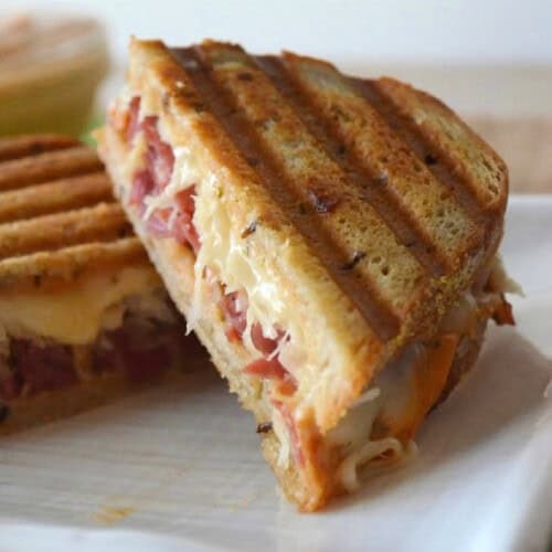 Two sandwiches with corned beef and sauerkraut on toasted bread.