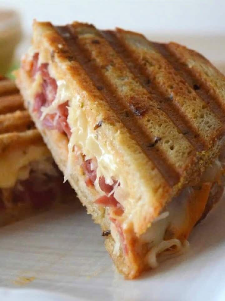 Two sandwiches with corned beef and sauerkraut on toasted bread.