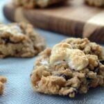 Close up of blueberry oatmeal marshmallow cookie with several other cookies blurred in background.