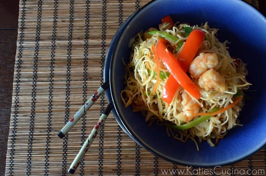 Bowl of Shrimp Veggie Lo Mein with chopsticks sticking out on bamboo placemat.