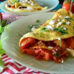 Cherry Tomato and Chorizo Omlet Plated decoratively next to Cilantro sprig and fork.