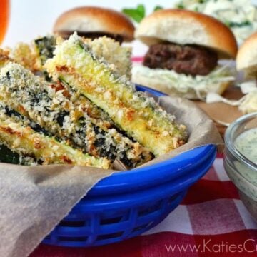 crispy baked breaded zucchini fries in a bowl next to dip with sliders in background.