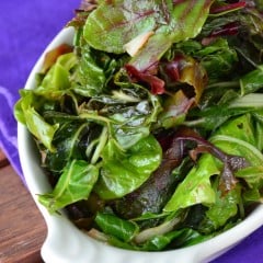 Vertical photo of sauteed Beet Greens and Swiss Chard in a white dish.