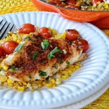 Browned fish topped with cilantro and cherry tomatoes on bed of fresh mexican corn salad.