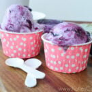 Two paper pink polka-dotted cups with one scoop of purple and white marbled ice cream.