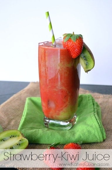 A single glass of strawberry kiwi juice over ice on a green cloth.