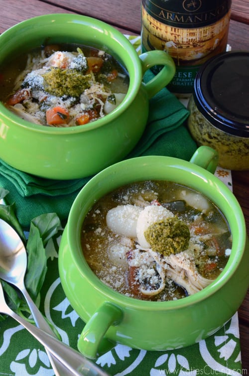 Two green crocks with soup, gnocchi, and pesto with jars in background.