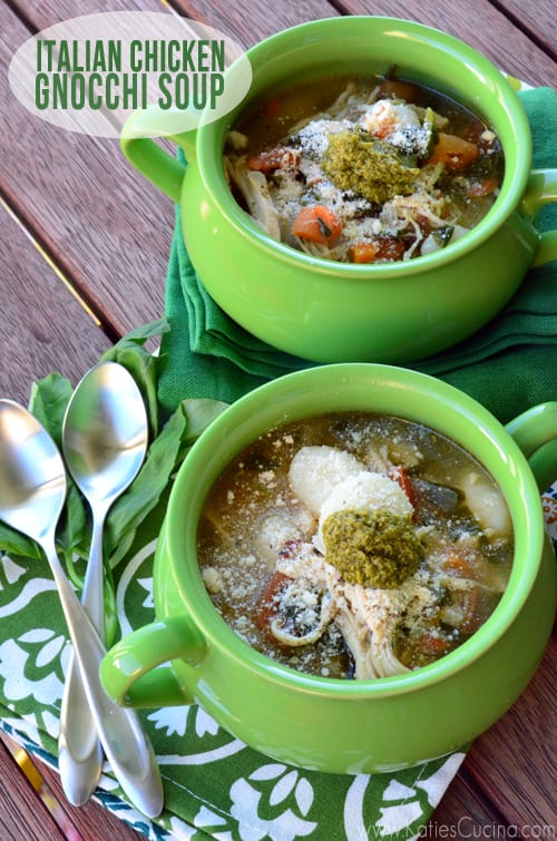 Two green crocks of soup with a floral napkin and two spoons.