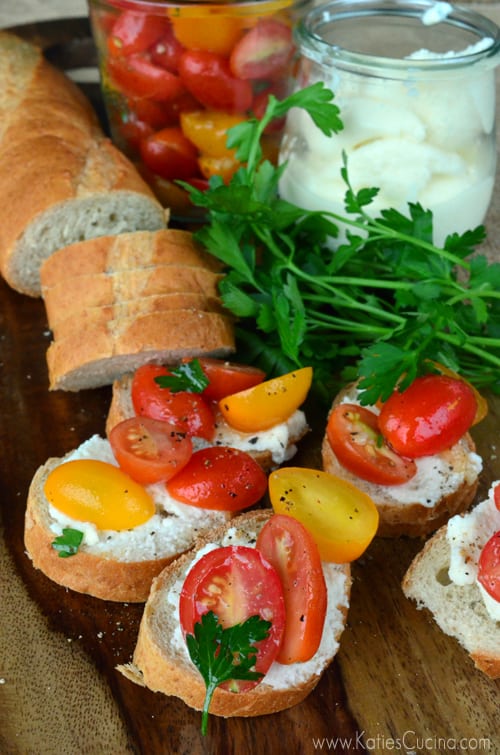 Sliced bread on a board topped with riccota and grape tomatoes