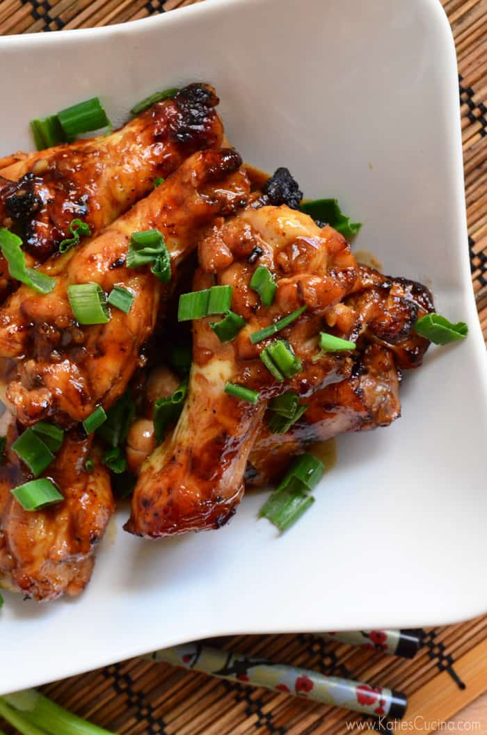 Top view of a chicken drumsticks topped with sliced green onions.