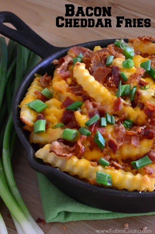 Black skillet filled with fries, bacon, cheese, and green onions.