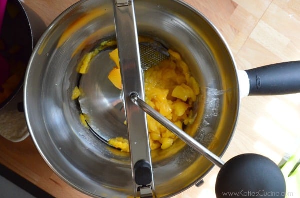 Top view of a food mill pureed peaches on a wood countertop. 