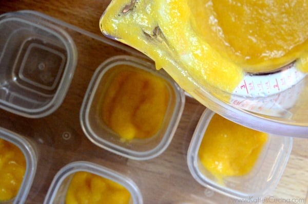 Top view of a measuring cup with orange puree and square storage containers half filled. 