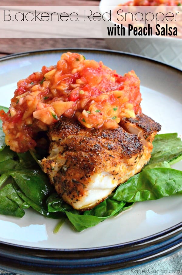 White plate with a piece of seasoned white fish on a bed of spinach topped with salsa.