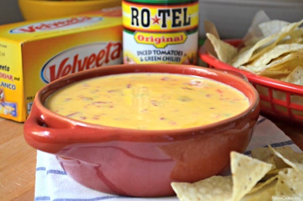Red bowl filled with queso cheese dip with Ro*TEL can and Velveeta block in background. 