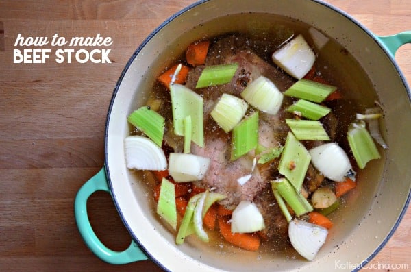 White pot with green handle filled with beef, carrots, onions, and celery in water with text on image.