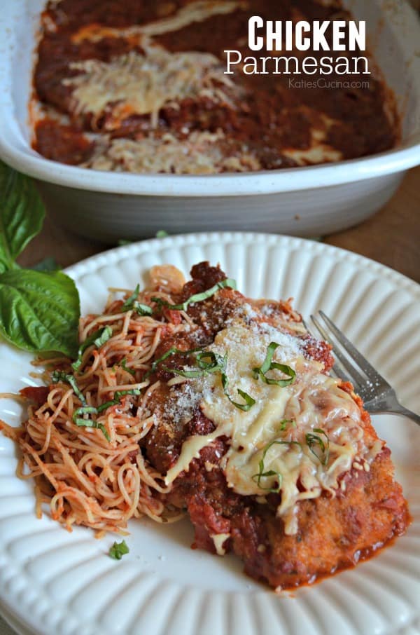 Close up of a piece of Chicken Parmesan on a white plate with pasta and text on image.