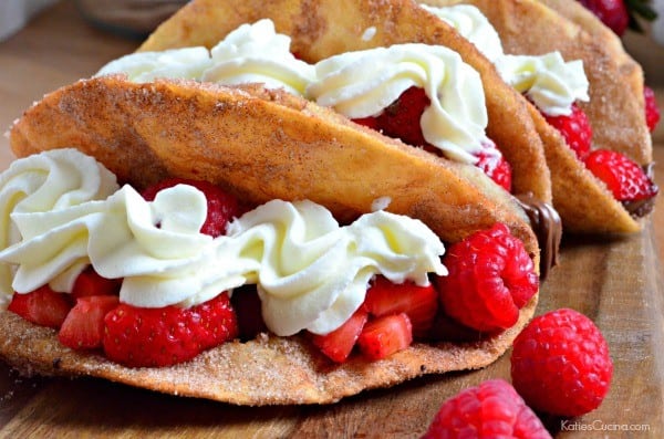 Close up of cinnamon sugar taco filled with strawberries and raspberries with whipped cream.