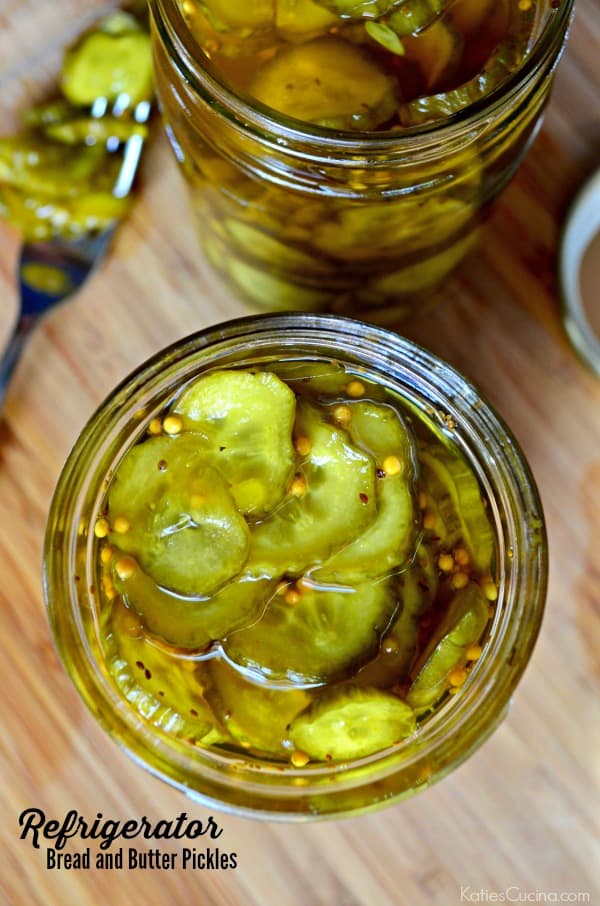 Top view of two mason jars filled with pickles on a wood cutting board.