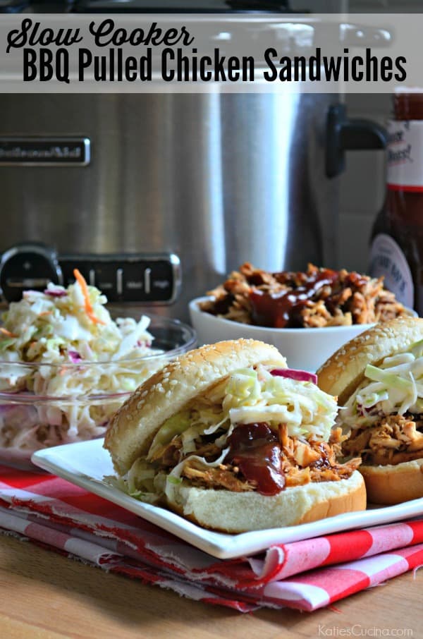 Pulled chicken sandwiches loaded with barbecue sauce and coleslaw on a white platter with red checkered cloth.