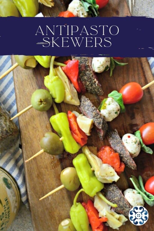 Top view of Antipasto Skewers on a wood board with text on image for pinterest.