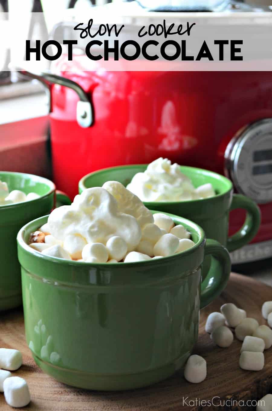 Red slow cooker in background with green mugs filled with whipped cream and text on image.