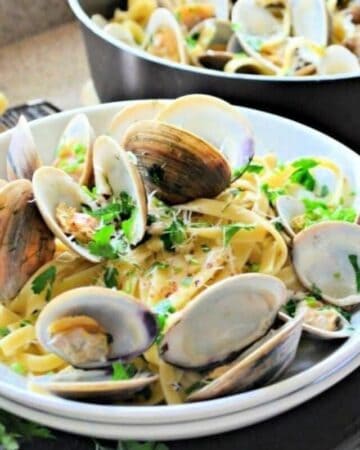 A bowl of fettucine pasta with clams and cilantro on top